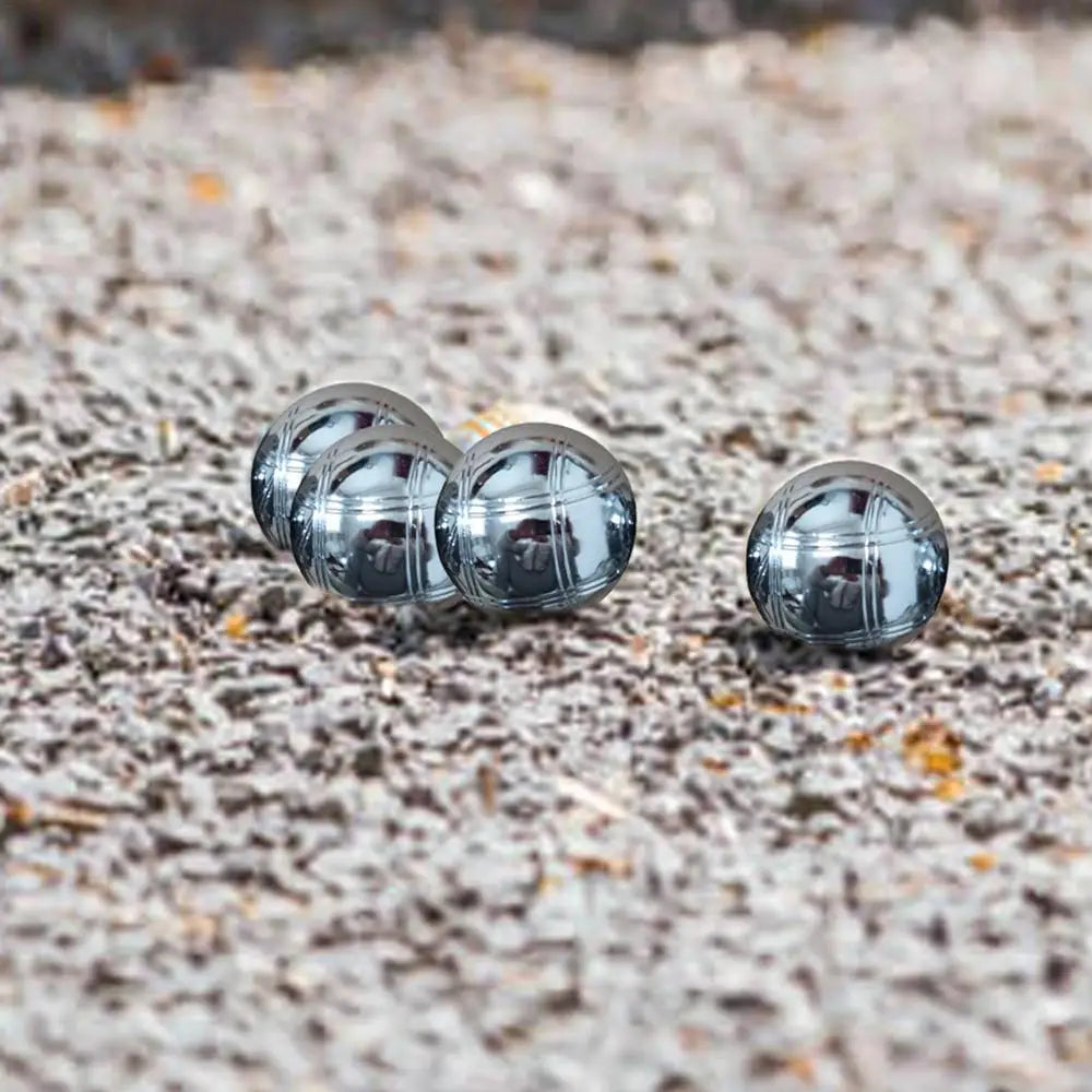 Ensemble de boules de pétanque en métal gravé, posées sur du gravier, parfait pour un jeu élégant et unique.