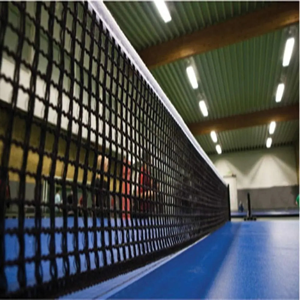 Portable retractable polyester ping pong net on blue table tennis surface in an indoor facility.