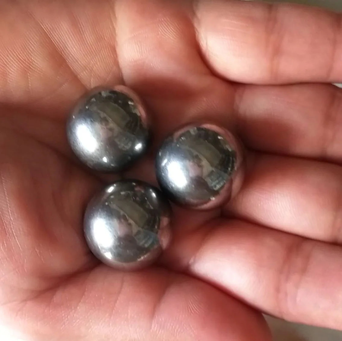 Close-up of three solid pétanque boules in a hand, showcasing their excellent quality and polished finish for guaranteed satisfaction