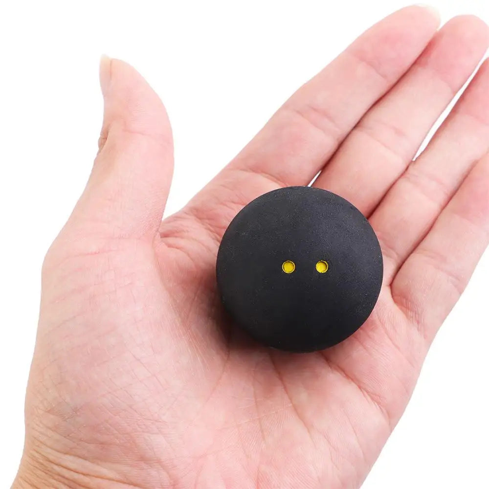 Squash ball with two yellow dots for professional training and competition in hand for scale