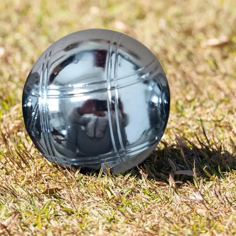 Boule de pétanque en métal gravé sur herbe verte, élégante et unique.