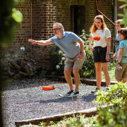 Man playing pétanque with friends outdoors, throwing a boule.